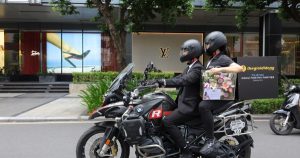 Shipper Thế Giới Di Động mặc vest đen, đi mô tô phân khối lớn để giao điện thoại cho khách
